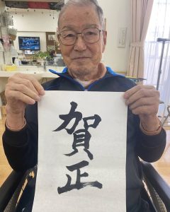 「賀正」の書初めを掲げる入居者様。特別養護老人ホームせとうちにて。
