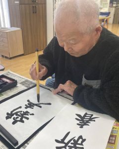 「新春」の文字を書く入居者様。特別養護老人ホームせとうちにて。